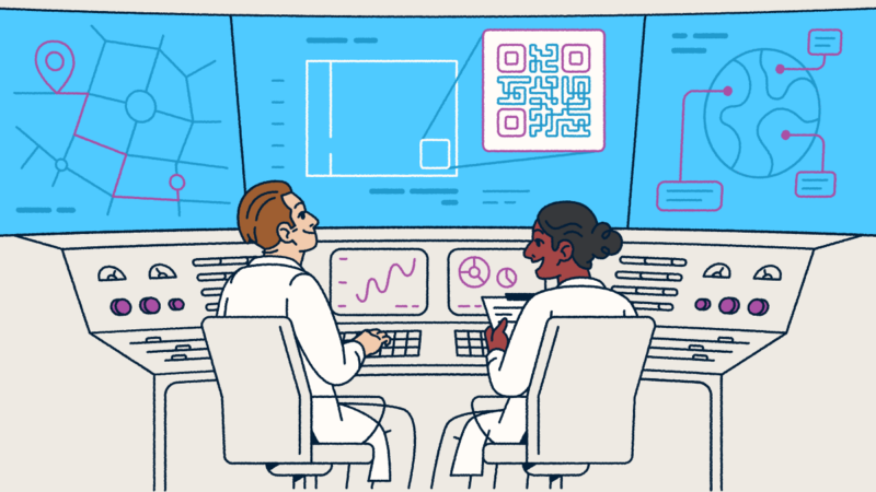 Two scientists sitting at a console looking at screens with QR Codes and graphs.