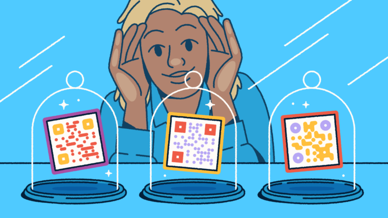 A person looking through a store-front window at three different QR codes on display in glass cloches.