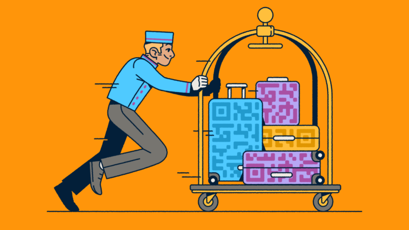 A bellhop pushing a luggage cart with several suitcases that have QR Code prints on them.