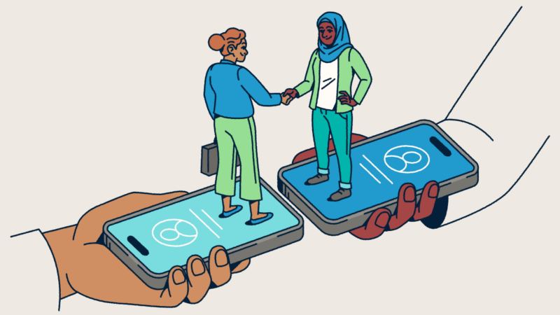 Two people standing on smartphones shaking hands.