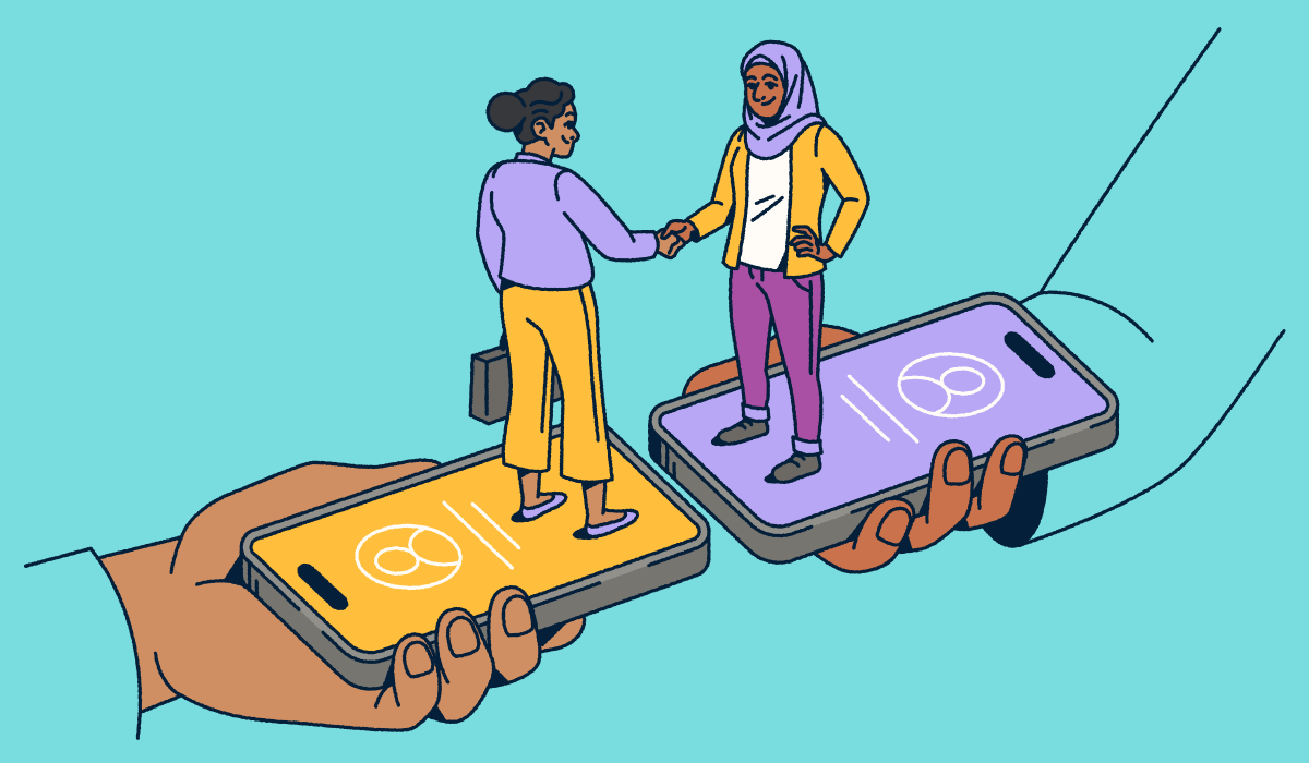 Two people standing on smartphones shaking hands.