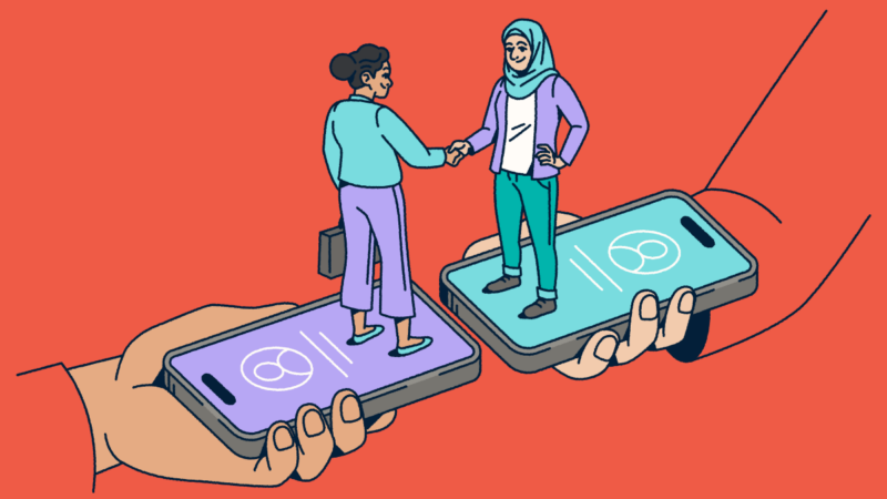 Two people standing on smartphones shaking hands.
