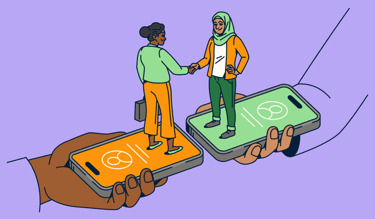 Two people standing on smartphones shaking hands.