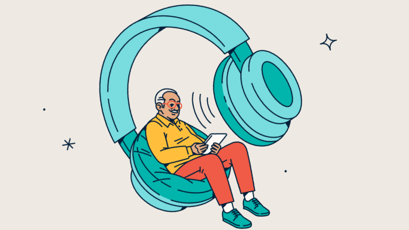 A person looking at a tablet while sitting in one side of a giant pair of headphones.