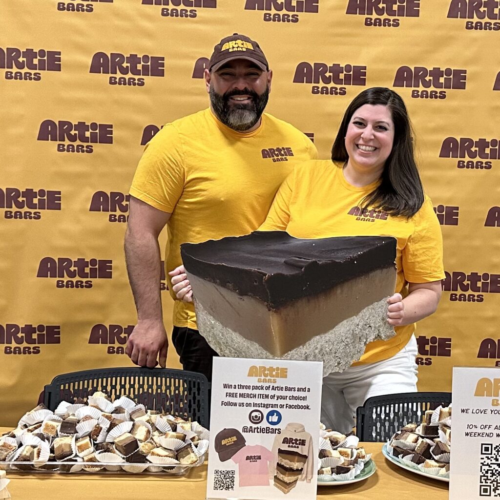 Artie and Nicole in front of an Artie Bars booth.