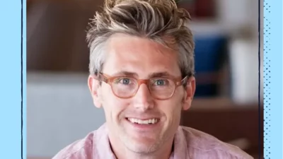 A headshot of a smiling man with glasses.