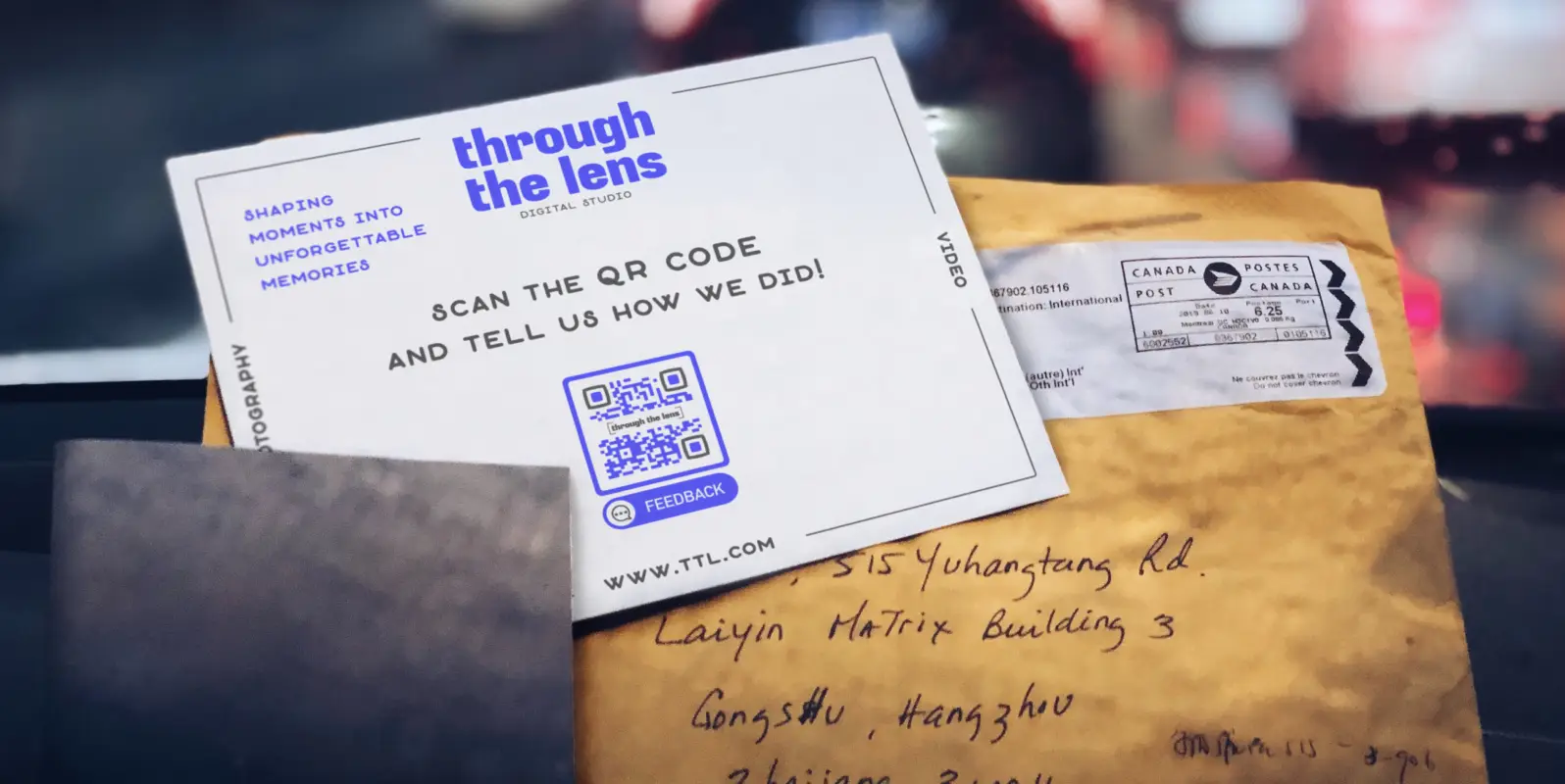 The front of a business card and the back of a business consultant's business card with contact information and a QR Code on it on top of the mailer it came in.