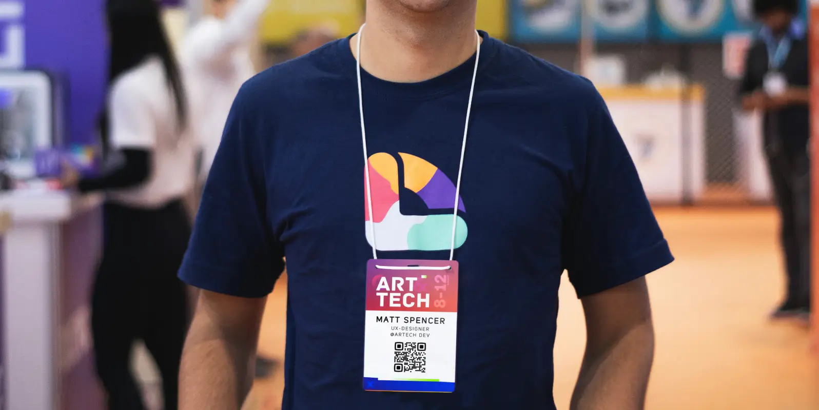 A man wearing a t-shirt and an event badge with a QR Code.
