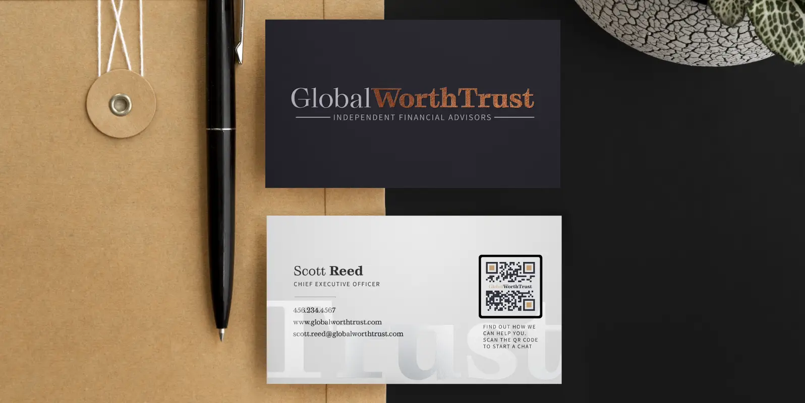File folder with a pen, black business card front, and business card back showing contact details and QR Code on it.
