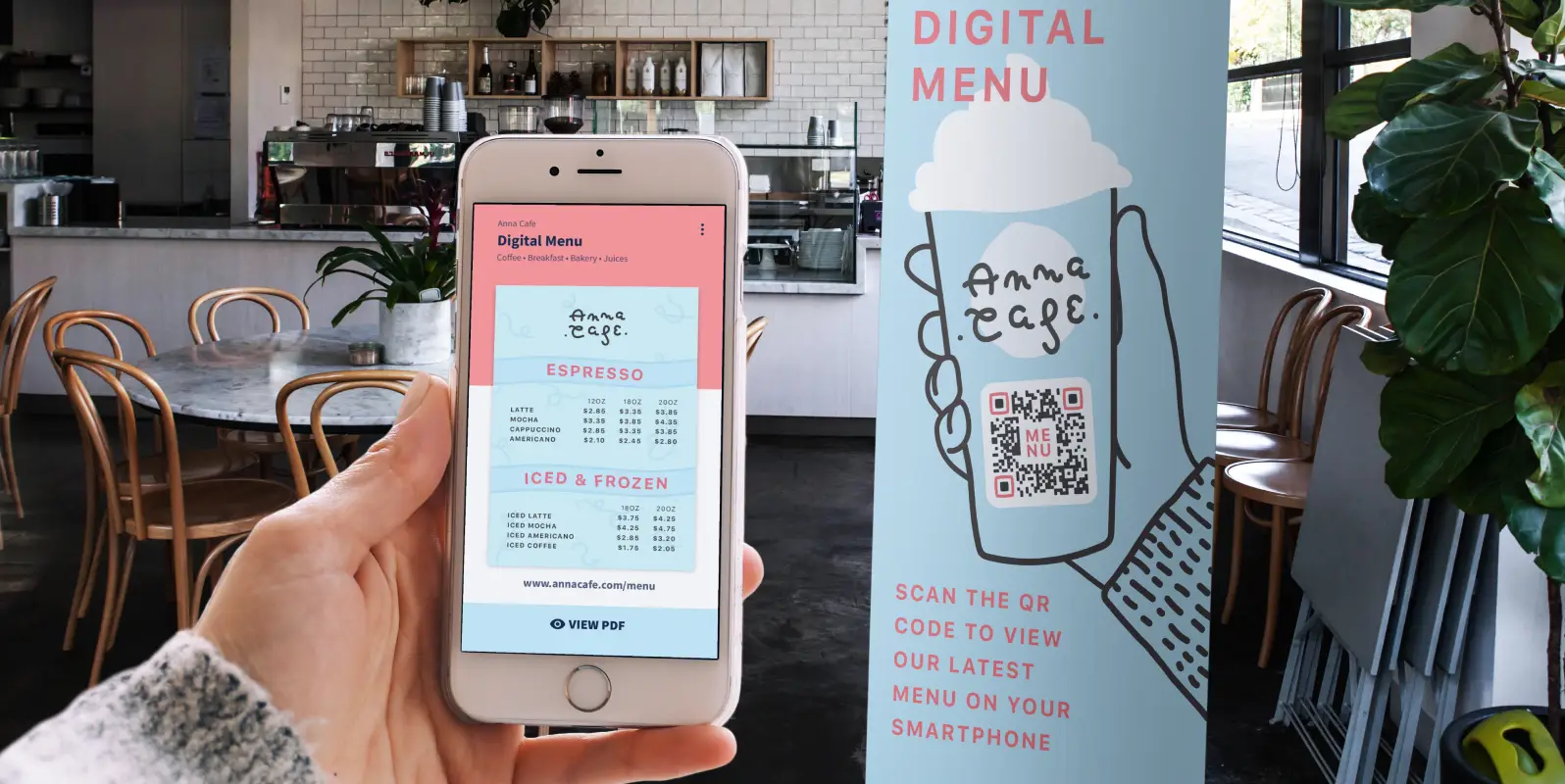 Hand holding an iPhone displaying a menu that was scanned from the QR Code on the cafe's banner in the background.